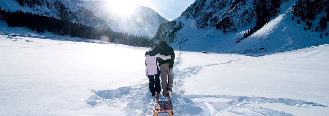 A father and daughter dragging a toboggan through the snow