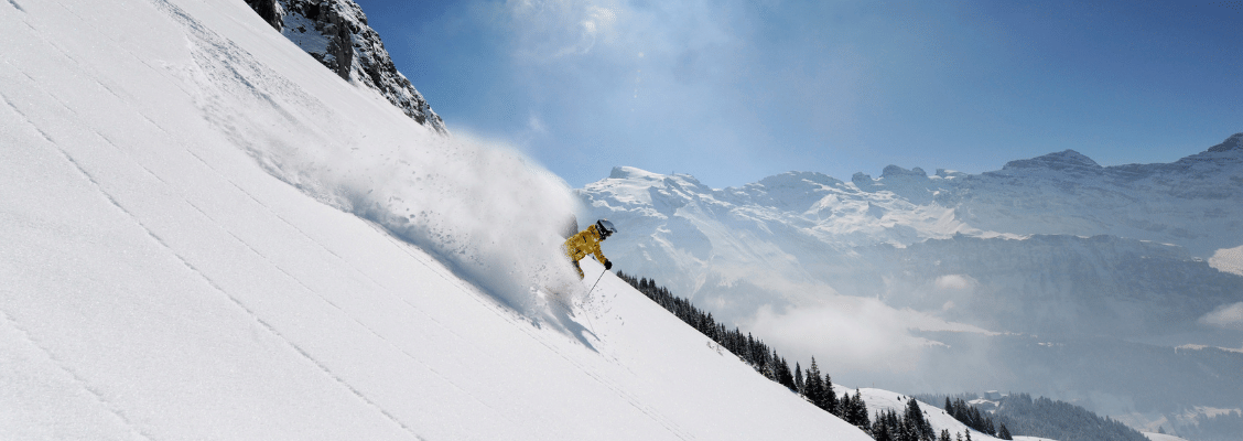 A skier skiing through powder snow on a steep mountain in Europe
