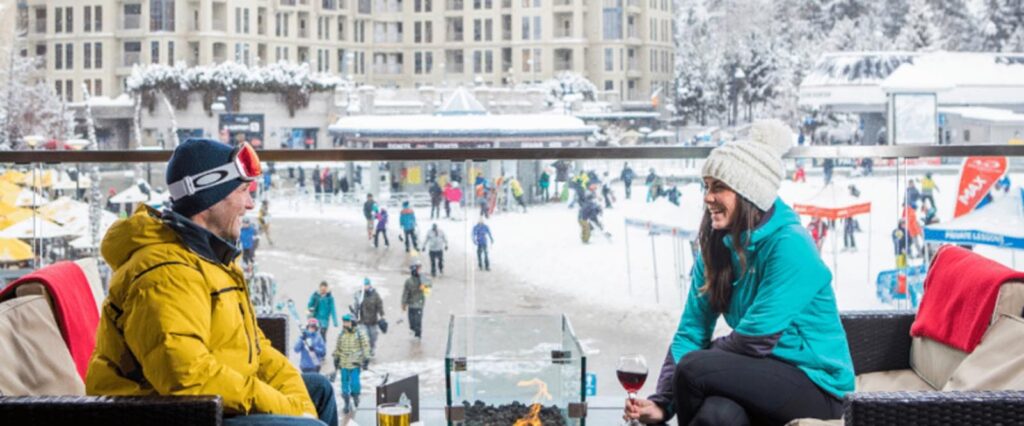Two people enjoying a drink on a balcony in the Canadian ski town of Whistler