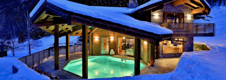 A snow-covered ski chalet with an outdoor pool