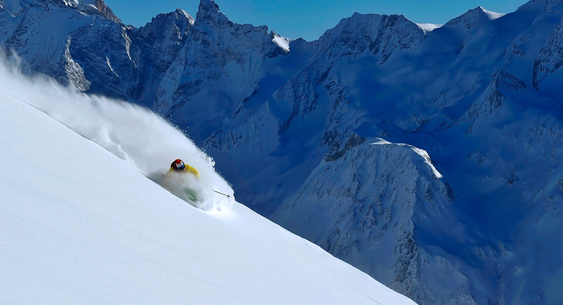 A skier in powder snow in front of a mountain range