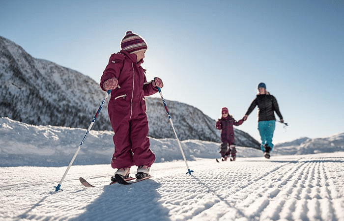A mother cross-country skiing with her kids